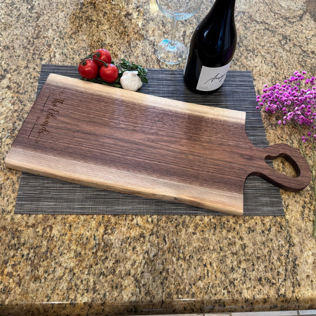 Live edge walnut charcuterie board with heart-shaped handle, wine, and fresh ingredients