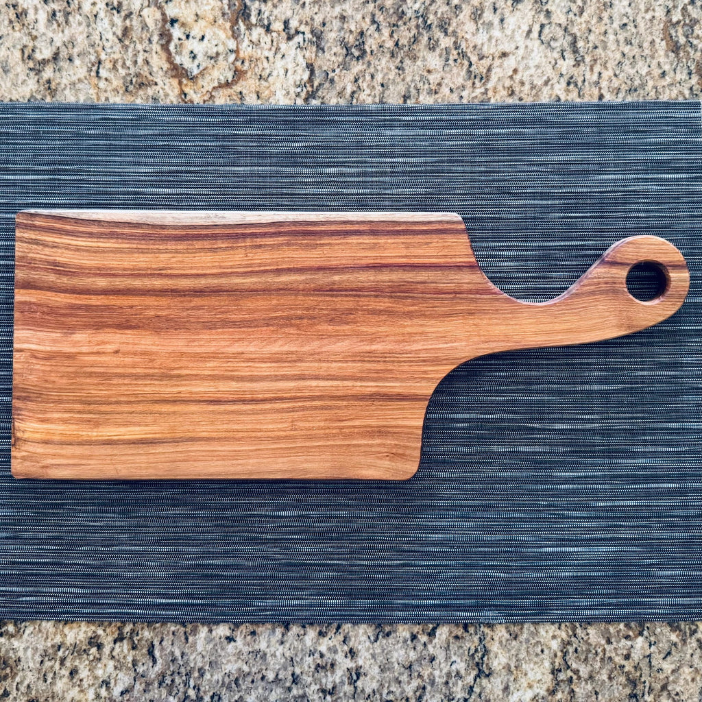 Canary wood charcuterie board with handle on kitchen countertop