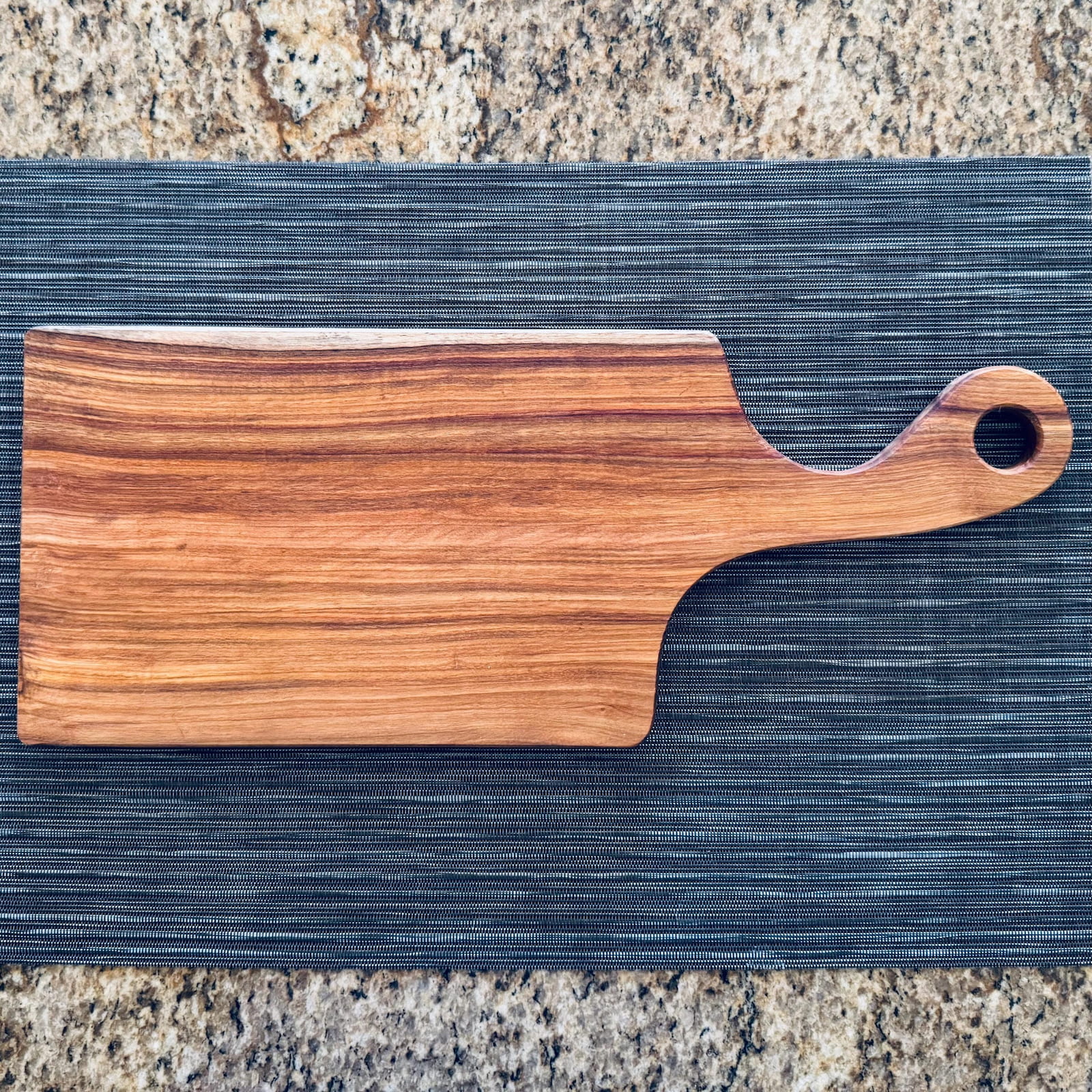 Canary wood charcuterie board with handle on kitchen countertop