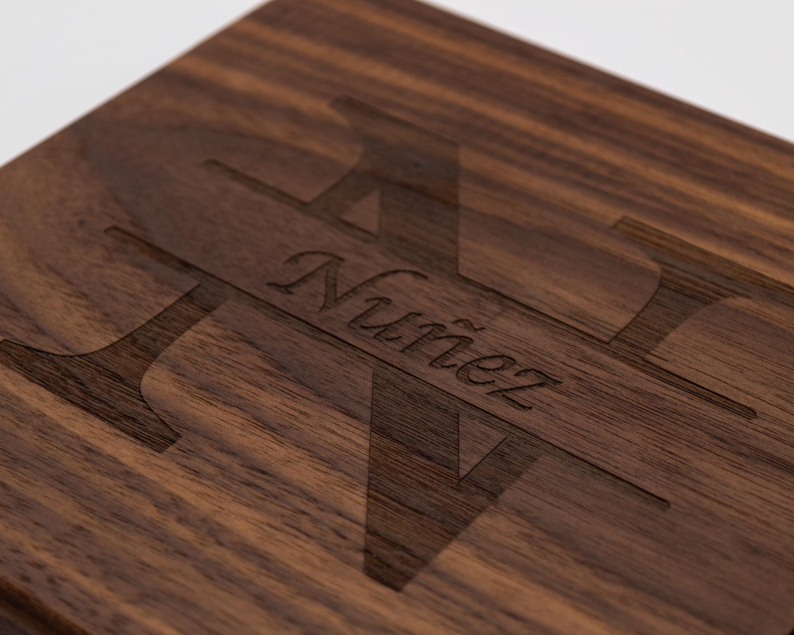 Close up of engraved split monogram family name design on walnut cheese slicer