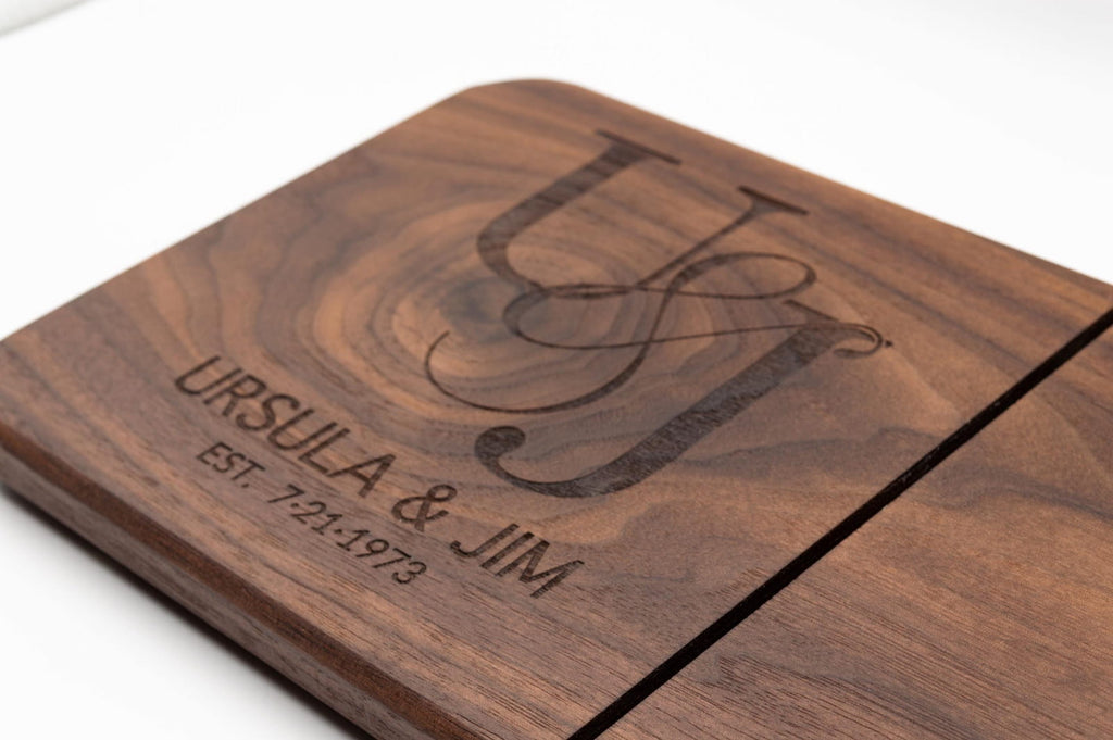 Close-up of personalized walnut cheese slicer engraved with couples monogram, names, and anniversary date