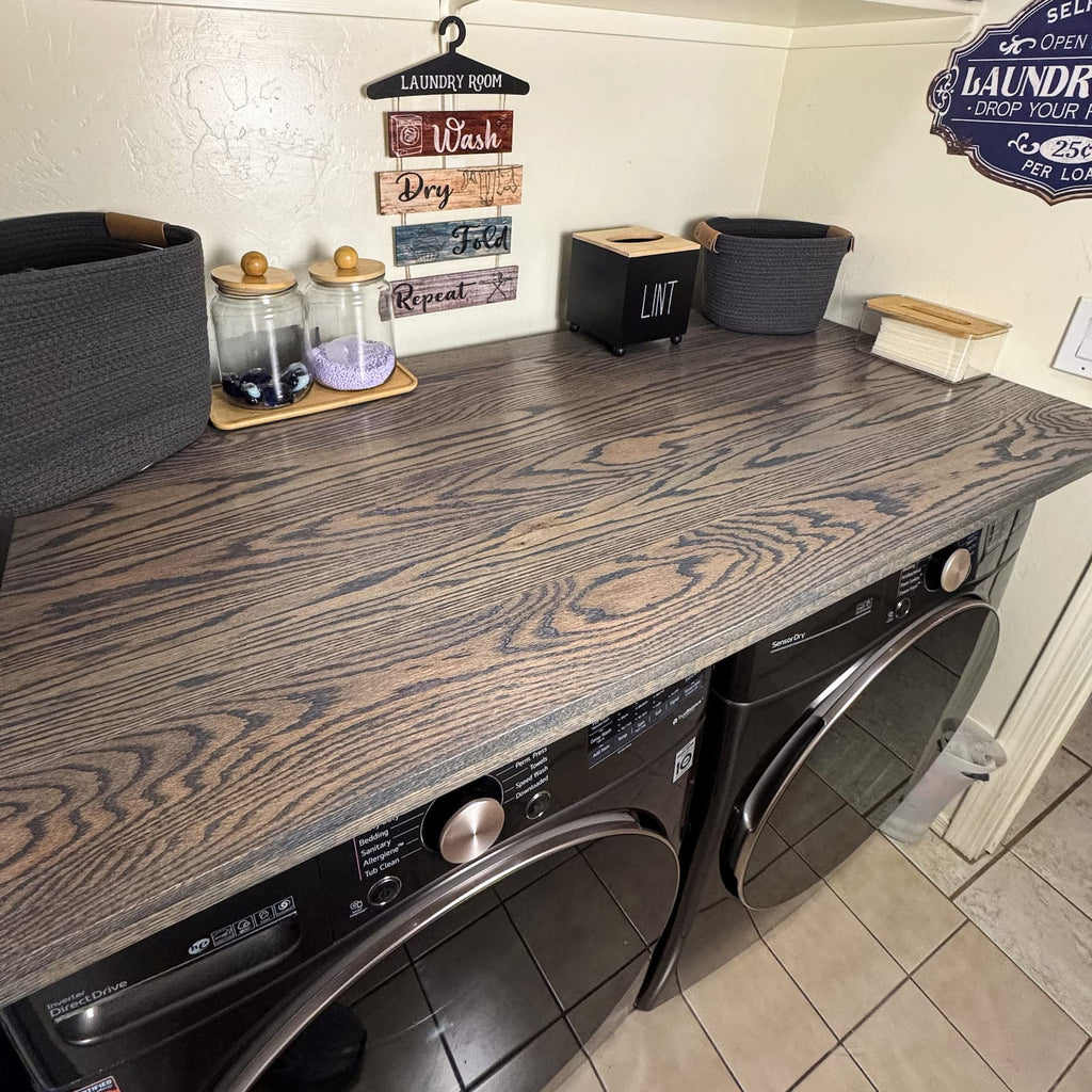 Dark oak laundry room countertop installed above black washer and dryer with farmhouse decor