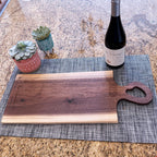 Live edge walnut charcuterie board with heart-shaped handle beside wine bottle