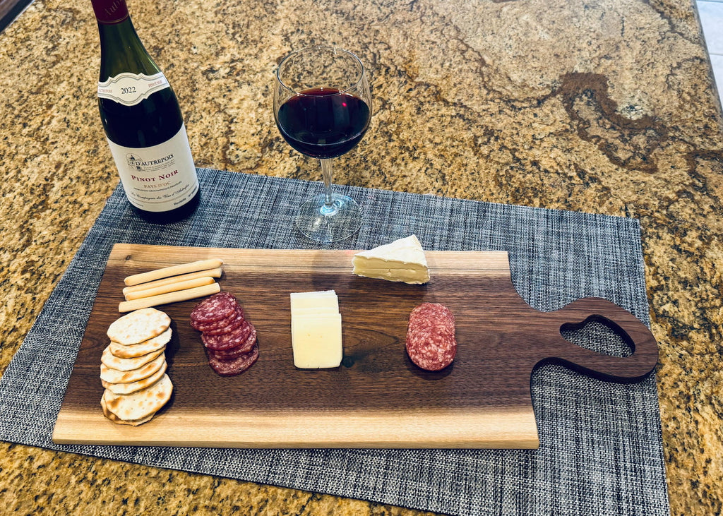 Live edge walnut charcuterie board with wine, cheese, crackers, and cured meats