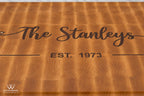 Close-up of dark wood Stanley family name and established date inlaid into maple end grain cutting board