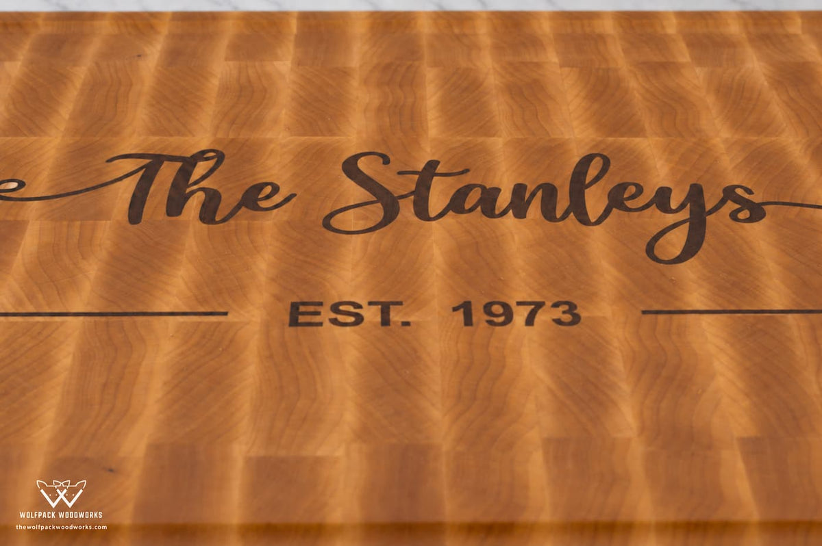 Close-up of dark wood Stanley family name and established date inlaid into maple end grain cutting board