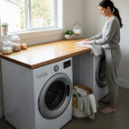 Modern oak laundry room countertop above front load washer and dryer with woman folding towels
