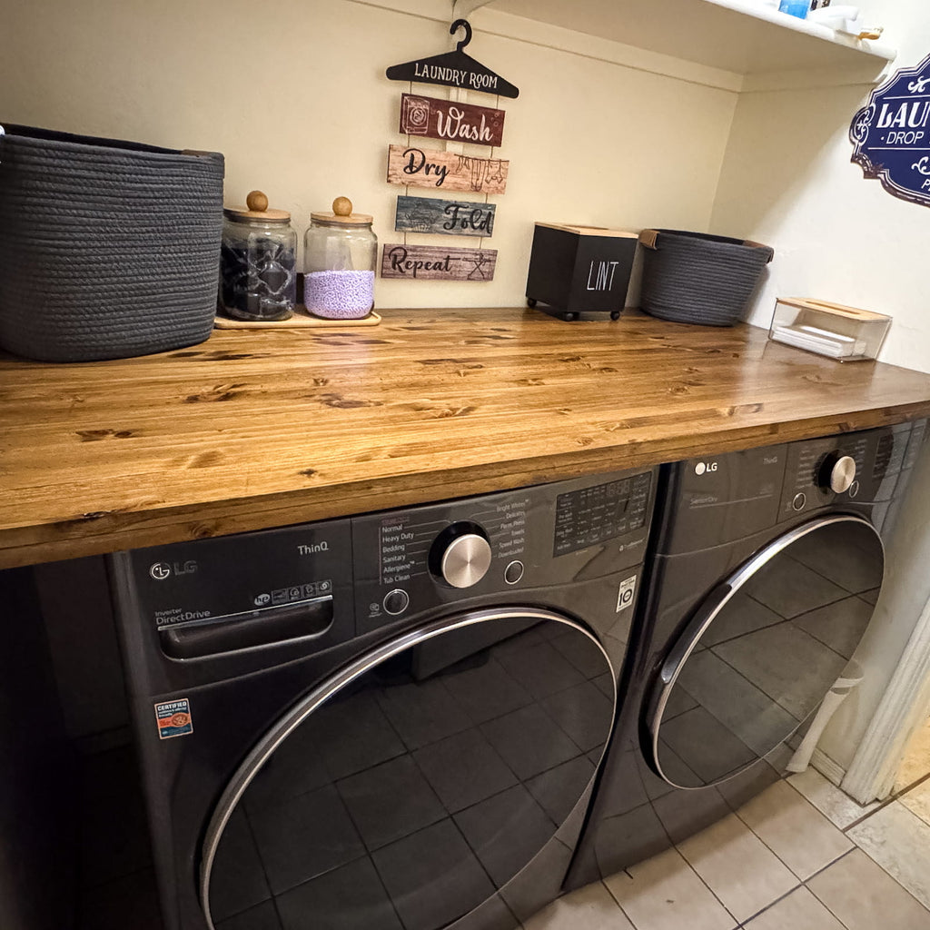Custom oak laundry room countertop installed over front-load washer and dryer