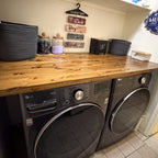 Custom oak laundry room countertop installed over front-load washer and dryer