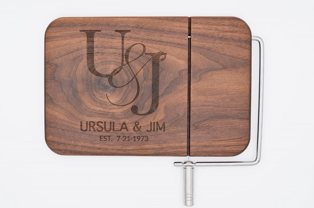 Personalized walnut cheese slicer with engraved couples monogram, names, and anniversary date on white background