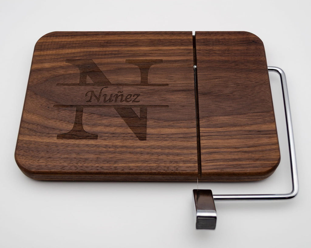 Personalized walnut cheese slicer with engraved split monogram and family name on white background
