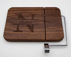 Personalized walnut cheese slicer with engraved split monogram and family name on white background