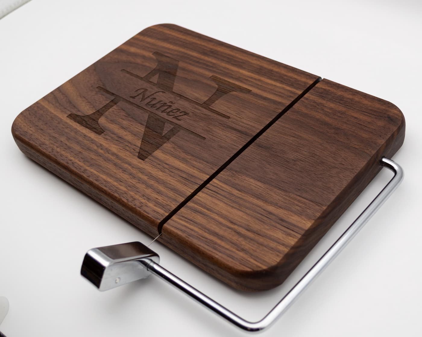 Personalized walnut cheese slicer with engraved split monogram family name design on white background