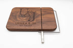 Personalized walnut cheese slicer engraved with couples monogram, names, and wedding date on a white background