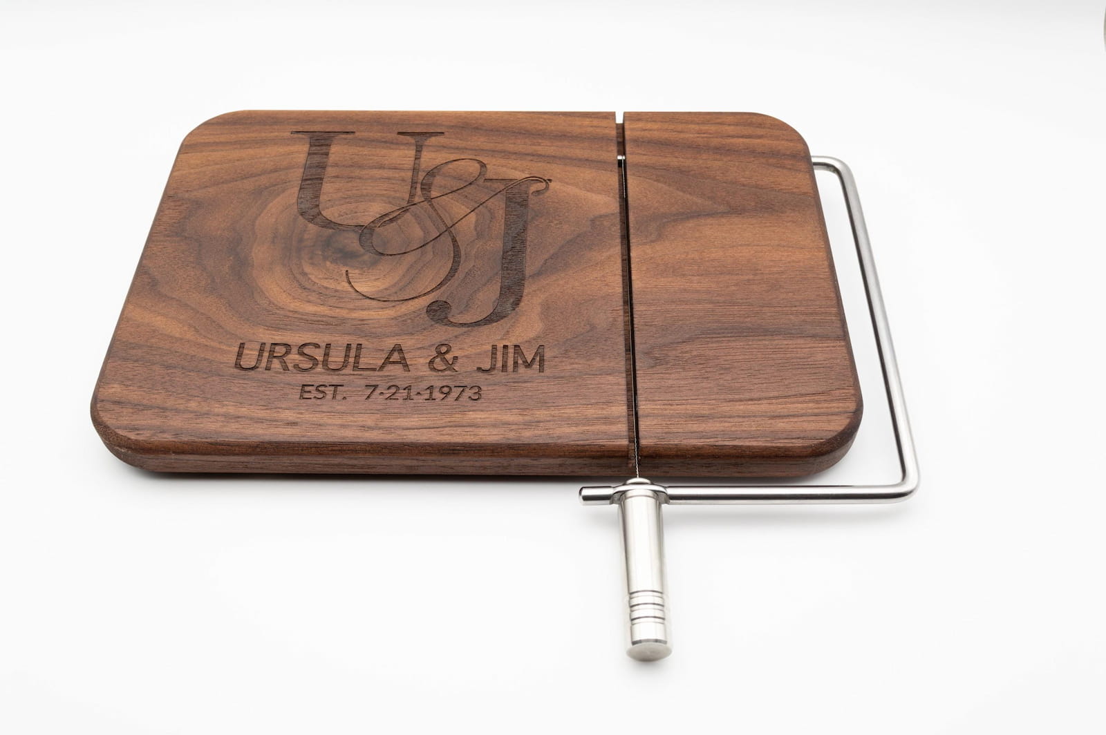 Personalized walnut cheese slicer engraved with couples monogram, names, and wedding date on a white background