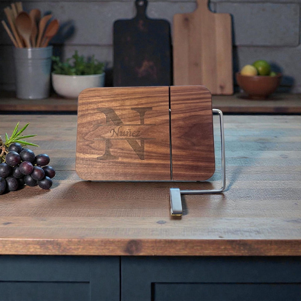 Personalized walnut cheese slicer with split monogram engraving displayed on a kitchen countertop with grapes