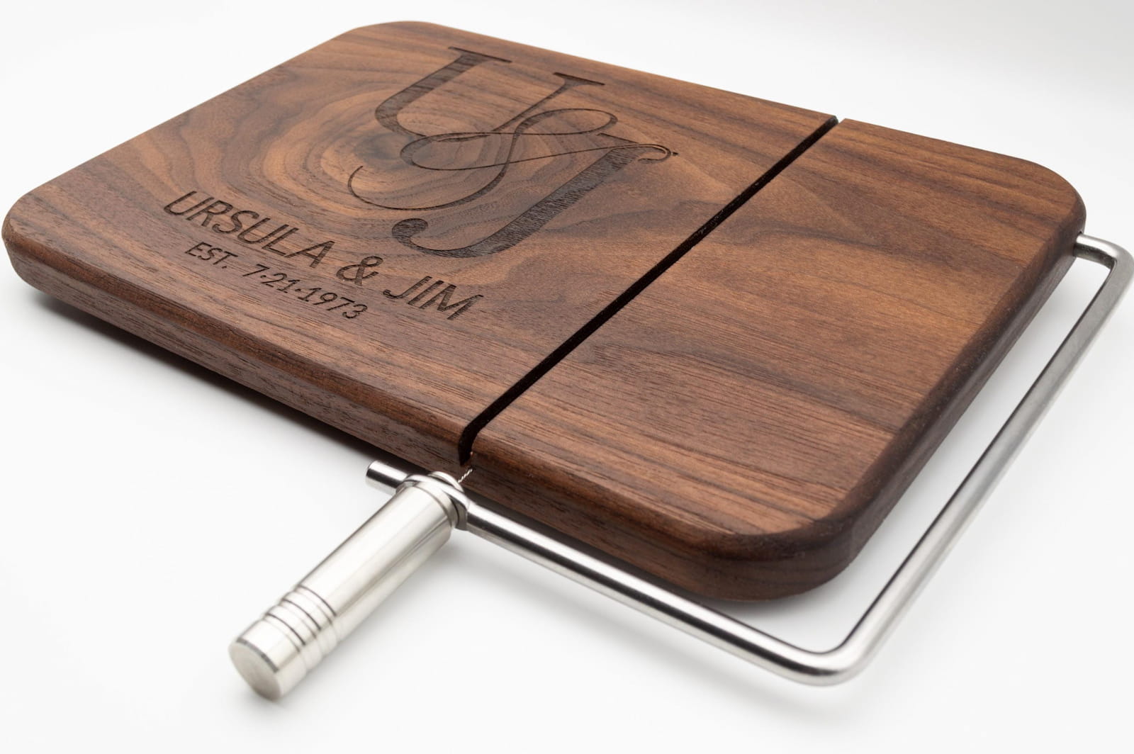 Personalized walnut cheese slicer with engraved couples monogram, names, and anniversary date on a white background