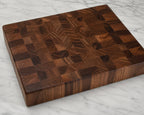 Handcrafted walnut end grain cutting board on marble countertop